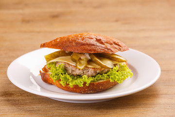 Delicious original american hamburger with grilled beef, bacon and vegetables on white plate, snack or lunch, product photography for restaurant or bistro