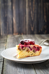Slice of homemade cranberry cake with walnouts, berries and powdered sugar on a ceramic plate. Space for text. Rustic style. Selective focus.