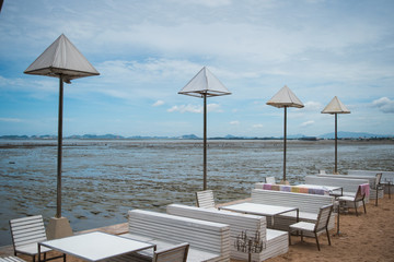 Beach chairs on the white sand beach with cloudy blue sky and su