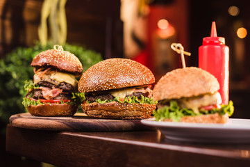 Three juicy and tasty burger with ketchup bottle on the table in a restaurant
