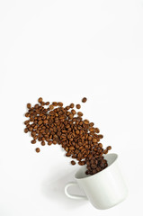 Spilled coffee beans from the white ceramic cup