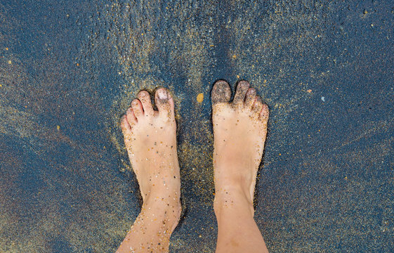 Black volcanic sand beach human caucasian person foot feet toes stand water 