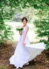 young beautiful bride in a white dress standing alone outdoors