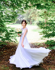 young beautiful bride in a white dress standing alone outdoors