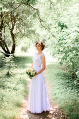 young beautiful bride in a white dress standing alone outdoors