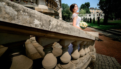 young and beautiful bride in white dress standing on the stairs