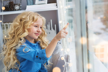 Smiling pretty little girl touches to the window