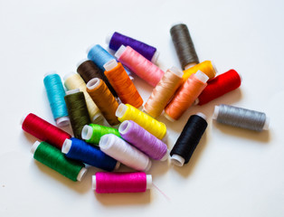 multicolored spools of thread on white background