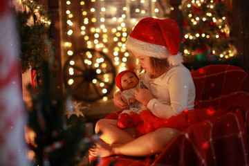Girl in Santa hat with  favorite toy doll by  fireplace, Christm