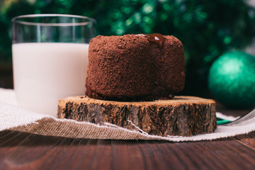 Chocolate cake, a glass of milk and Christmas decorations on woo