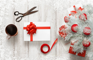 Gift wrapping for Christmas. Christmas tree with decorations beside. Top view of table with...