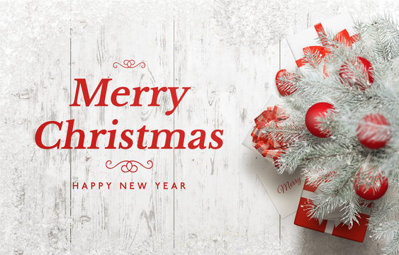 Merry Christmas and Happy New Year greeting card. Christmas tree on white wooden table with snow.
