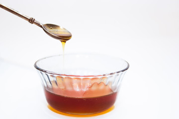 abstract background: honey flowing down from a silver spoon in a glass Cup