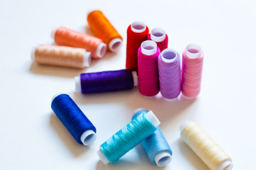 multicolored spools of thread on white background