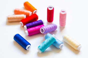 multicolored spools of thread on white background