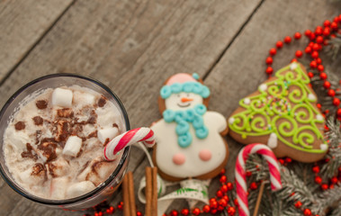 christmas background, composition. spruce branches, gingerbread (Snowman and Christmas tree), cocoa with cream and marshmallows, cinnamon, candy cane.