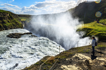 tourists watching rainbow on waterfall in Iceland