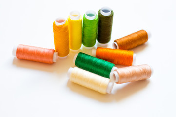multicolored spools of thread on white background