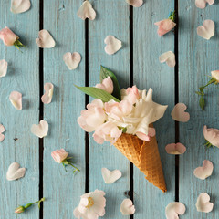 White flowers in icecream cone on wooden background. Summer patt