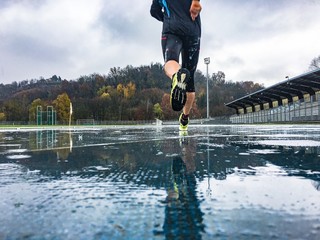 Man running on athletic track in a rainy day