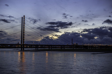 Fototapeta premium Beleuchtete Rheinkniebrücke in Düsseldorf an einem wolkenverhangenen Abend