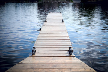 Naklejka premium Long old wooden pier in water at summer time