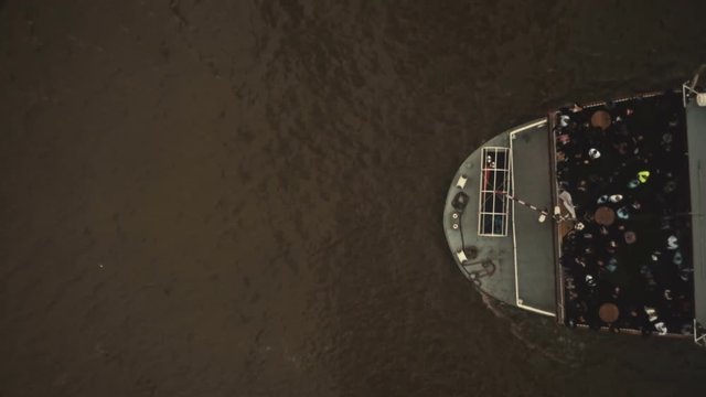 A top down view of a large paddle steamer making its way under the bascule-operated Tower Bridge in London, England, UK with its lifts seen closing to their initial position
