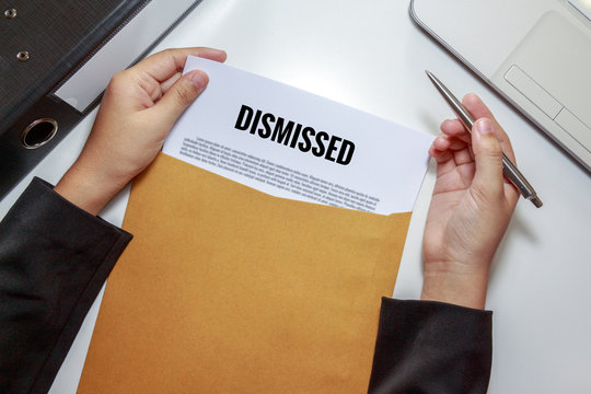 Businesswoman opening Dismissed document in letter envelope.