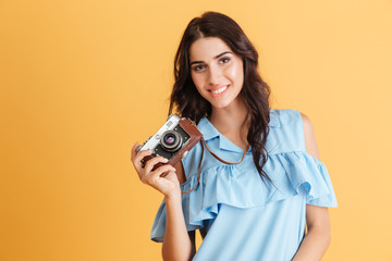 Fototapeta premium Portrait of a smiling young brunette girl holding photo camera