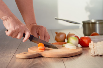Hands cutting carrots on a cutting board. Woman cutting vegetables in the kitchen 