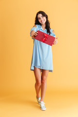 Smiling brrunette woman in blue dress showing gift box