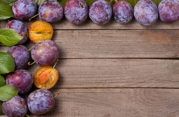 frame of plums on the old wooden background