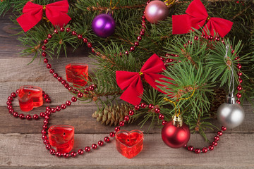 Christmas composition of fir branches decorated bows and balls with candles in shape  heart on a wooden background