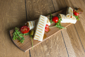 Wrap sandwich with salami and bacon , lettuce, tomatoes, ruccola, green olives