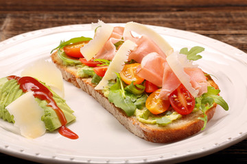 Avocado sandwich on fresh bread with arugula ham tomato and chee