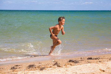 Boy running from sea on beach