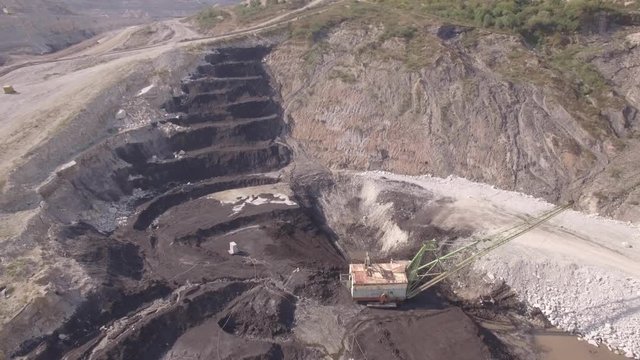 Aerial view on bucket wheel excavator and big dump truck in coal mine.
