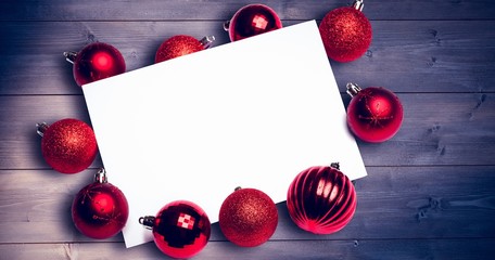 Composite image of red christmas baubles surrounding white page