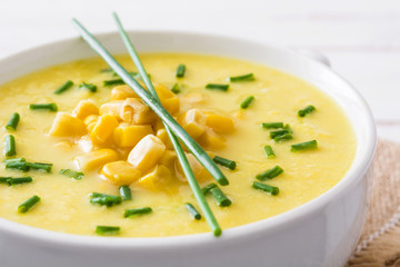 Corn soup in white bowl on wooden background.
