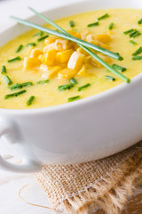 Corn soup in white bowl on wooden background.
