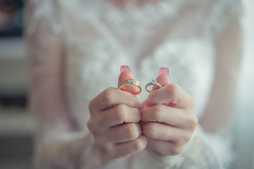 close up bride holds beautiful wedding ring on hand.