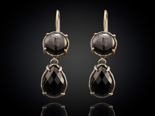 Golden earrings with gemstone isolated on black background