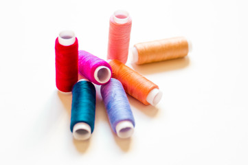 multicolored spools of thread on white background