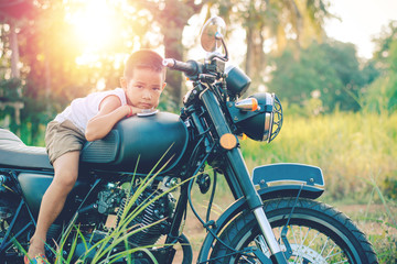 Little kid  on classic motocycle in park.