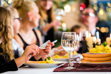 Mutter, Vater, Kinder feiern Weihnachten, essen traditionell Wiener Würstchen und Kartoffelsalat