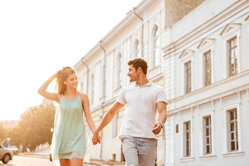 Happy romantic young couple in love walking and holding hands