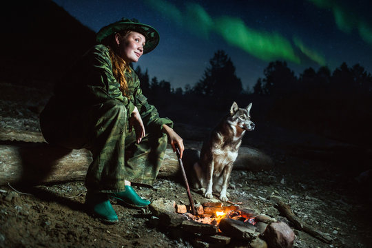 Tourist Girl With Her Dog Around Campfire At Misty Landscape Night Stars And Aurora Borealis