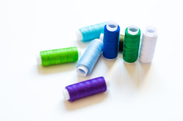 multicolored spools of thread on white background