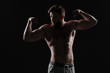 Naked athletic man demonstrates biceps