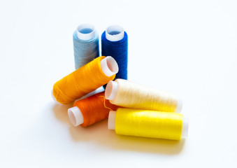 multicolored spools of thread on white background